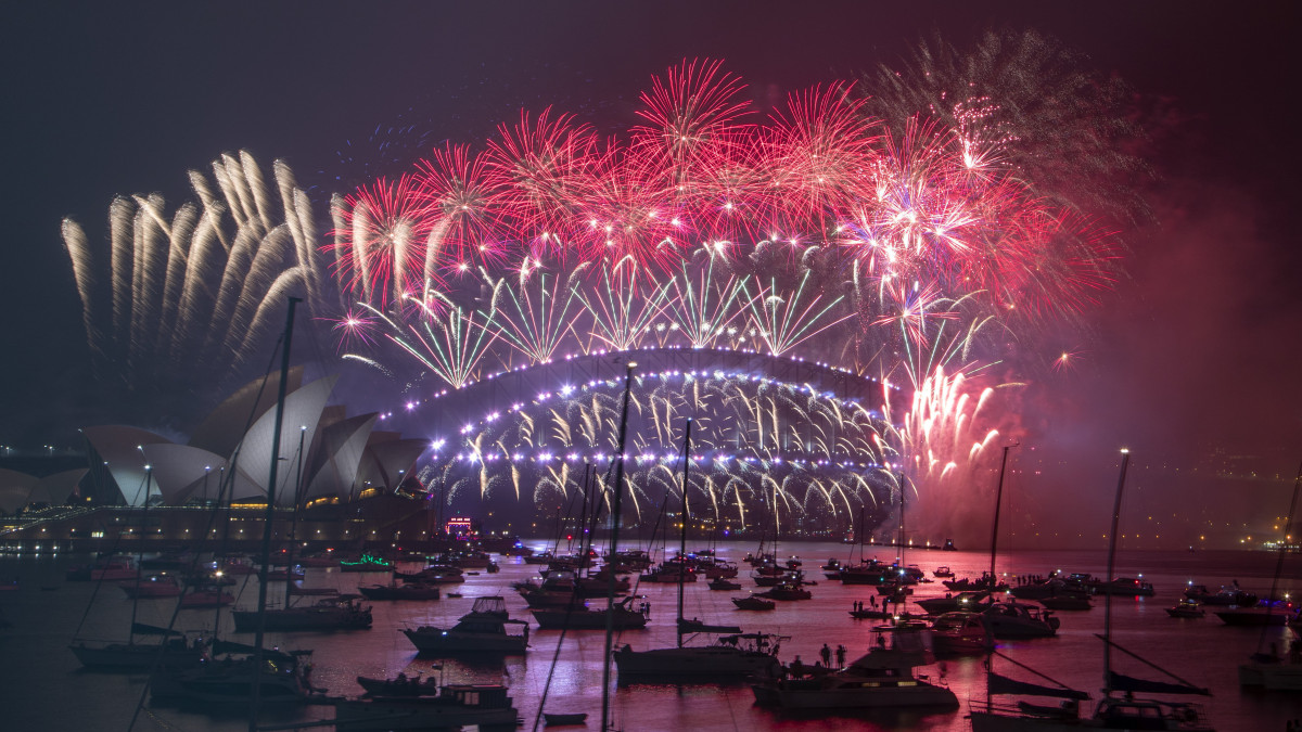 Tűzijátékkal köszöntik az új évet Sydney kikötőjében 2021. január 1-jén, szilveszter éjszakáján. Balról az Operaház épülete. A koronavírus-járvány miatt a hatóságok arra kérték a lakosságot, hogy otthonukban, televíziós közvetítésen keresztül kövessék az újévi ünnepségeket.