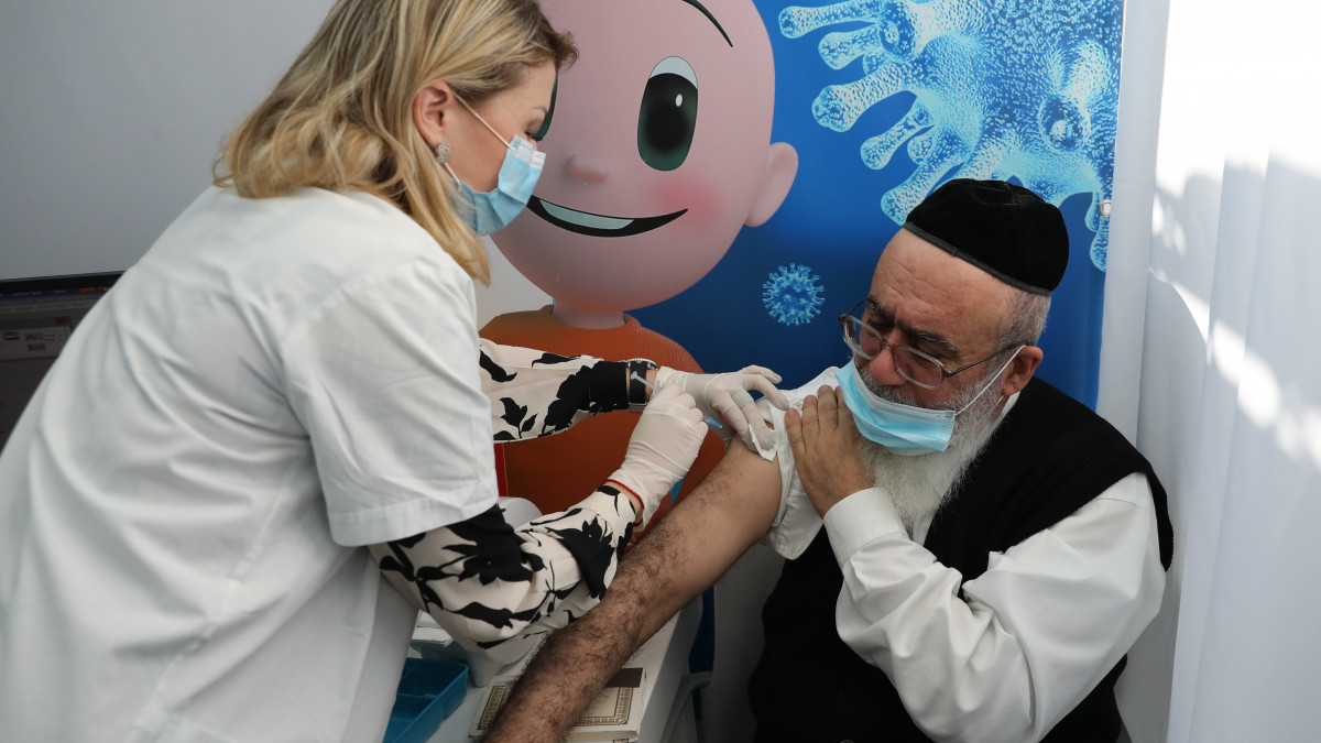 Koronavírus elleni vakcinát adnak be egy férfinak egy tel-avivi oltóközpontban 2020. december 22-én. Izraelben az egészségügyi dolgozók, a 60 éven felüliek és az egészségi okokból veszélyeztetett csoportokhoz tartozó emberek oltásával december 20-án kezdődött meg az új koronavírus elleni védőoltások beadása.