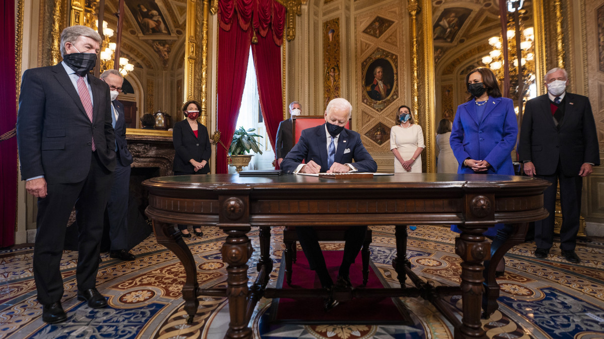 Joe Biden amerikai elnök (k) Kamala Harris alelnök (j) társaságában aláírja a beiktatási, valamint a kormányzati tisztségekre jelölt személyek jelöléséről szóló dokumentumokat a törvényhozás washingtoni épületében, a Capitolium elnöki irodájában 2021. január 20-án, beiktatása napján.