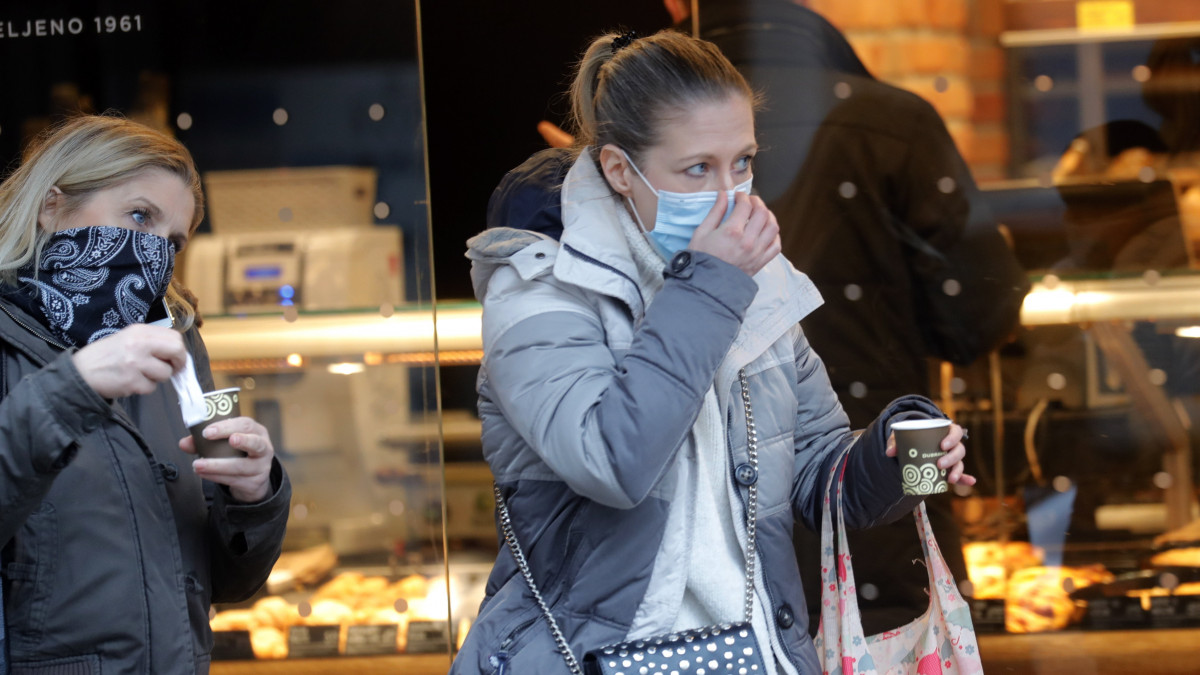 A koronavírus-járvány miatt védőmaszkot viselő járókelők elvitelre vásárolt kávéval egy zágrábi utcán 2021. január 29-én. Az előző 24 órában 619 új fertőzöttet azonosítottak Horvátországban.