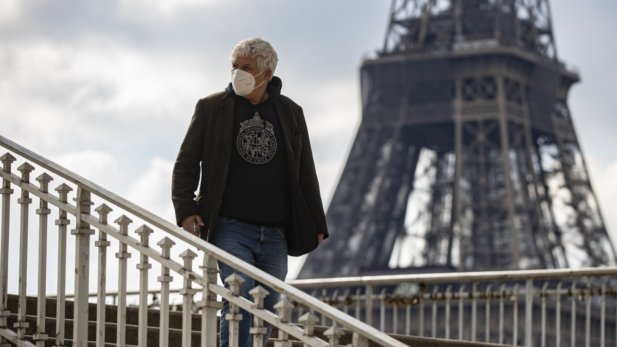 Üres gyaloghídon sétál egy férfi a párizsi Eiffel-torony közelében 2021. március 19-én, amikor tömegesen utaznak a francia fővárosban élők a vidéki országrészekbe. A koronavírus-járvány megfékezésére száz francia megyéből tizenhatban, köztük a francia fővárosban éjfélkor lép életbe a harmadik lezárás, amelyet legalább négy hétre rendelnek el.