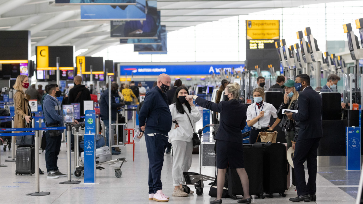 A member of staff directs passengers at check-in desks in Terminal 5 at London Heathrow Airport in London, U.K., on Monday, May 17, 2021. After a year of false starts, rogue virus strains and vaccine drama, Brits are finally able to travel again, if only to a handful of green list destinations that wont require quarantine on return. Photographer: Jason Alden/Bloomberg via Getty Images