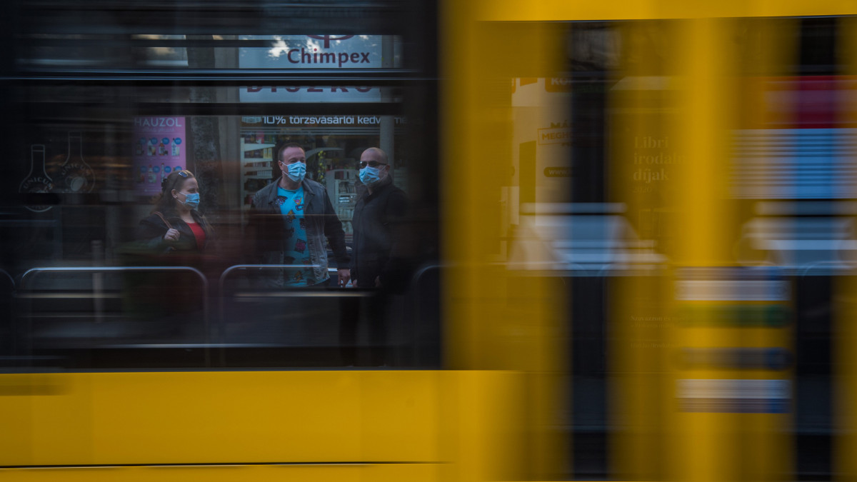 Védőmaszkot viselő utasok a Wesselényi utca villamosmegállóban 2020. április 27-én. Ettől a naptól csak sállal, kendővel vagy maszkkal eltakart arccal szabad felszállni a fővárosi tömegközlekedés járataira, s így lehet csak boltba menni és taxival utazni a koronavírus-járvány terjedésének megakadályozása érdekében. Az intézkedés nem vonatkozik a 6 éven aluli utasokra. A rendelkezés betartásának elősegítése érdekében a Budapesti Közlekedési Központ (BKK) és a Főpolgármesteri Hivatal több csomópontban mosható és vasalható textilmaszkot oszt az utazóknak.
