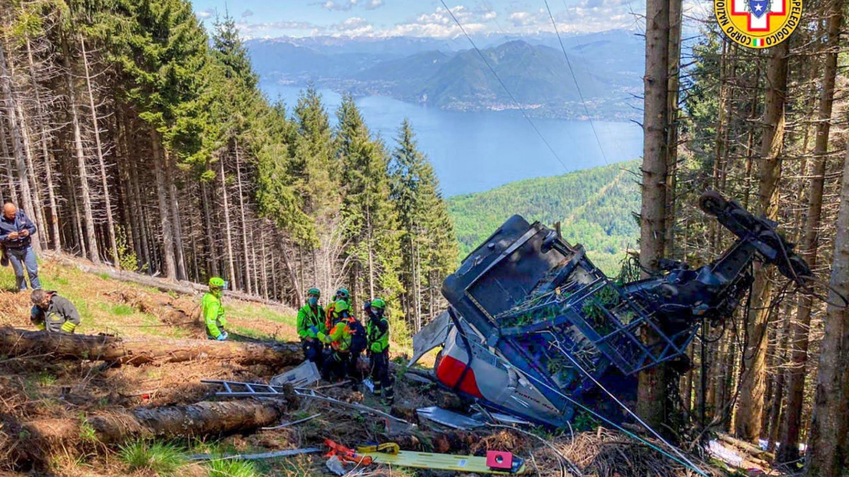 Az olasz nemzeti hegyimentő szolgálat (CNSAS) által közreadott kép a mentőcsapat tagjairól az észak-olaszországi Stresa települése és a Mottarone-hegy között közlekedő függővasút egyik lezuhant fülkéje mellett Verbania közelében 2021. május 23-án. A balesetben legkevesebb kilencen életüket vesztették.