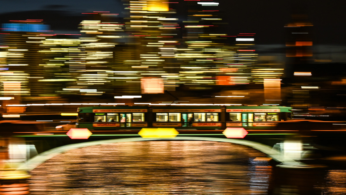 17 February 2021, Hessen, Frankfurt/Main: A tram crosses the Ignatz Bubis Bridge in the evening in front of the illuminated skyscrapers of the banking city. (Shot with slower shutter speed) Photo: Arne Dedert/dpa (Photo by Arne Dedert/picture alliance via Getty Images)
