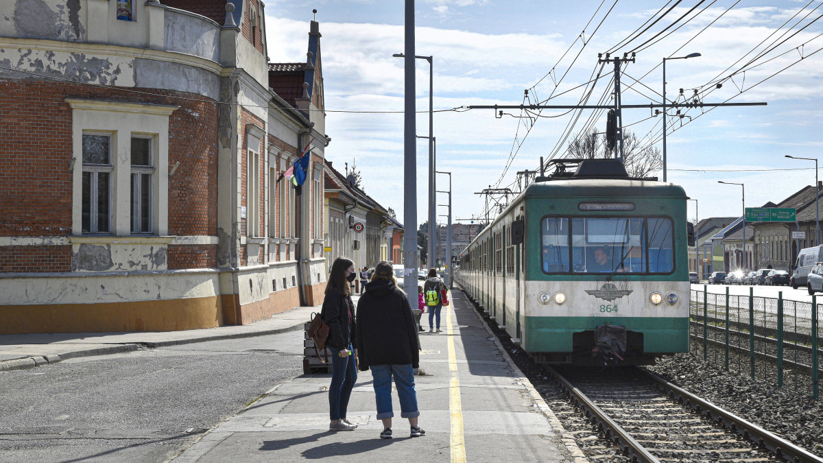 Budapest, 2021. március 29. A H6-os HÉV Budapest egyik elővárosi vasútvonalának szerelvénye, amelyet a MÁV-HÉV Helyiérdekű Vasút Zrt. közlekedtet, érkezik Ráckevéről a Soroksár, Hősök tere megállóba. Soroksár Budapest XXIII. kerülete a magyar főváros legfiatalabb kerülete, miután 1994-ben vált le Budapest XX. kerületéről. Balra a Galambos János Zenei Alapfokú Művészeti Iskola épülete. MTVA/Bizományosi: Róka László
