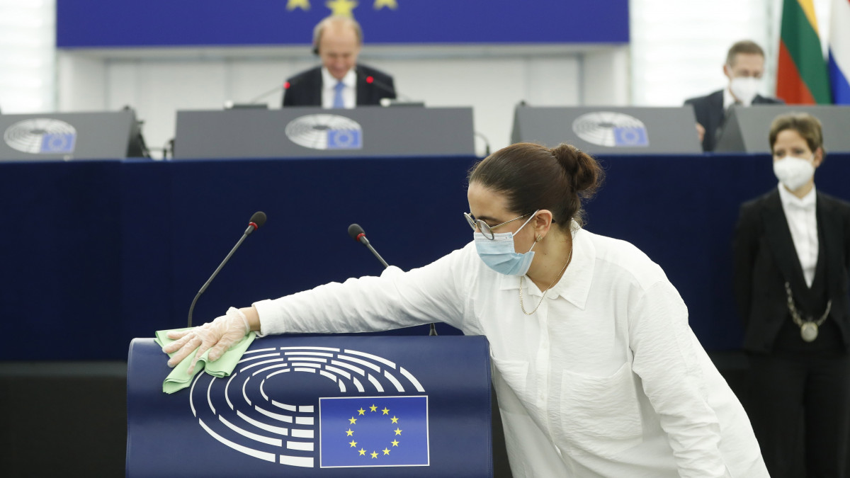 A szónoki pulpitust törli le egy takarító az Európai Parlament strasbourgi üléstermében 2021. június 8-án, amikor a koronavírus-járvány miatti 15 hónapos szünet után ismét plenáris ülésre várja a képviselőket a terem.