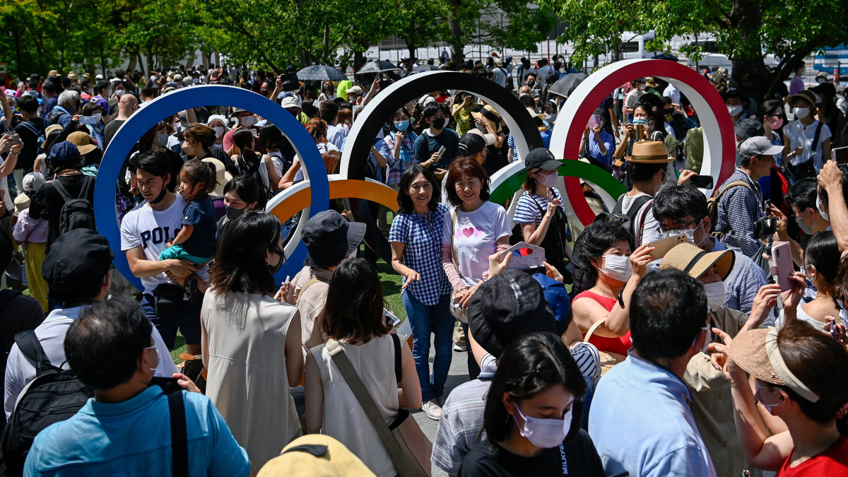 Helyiek fényképezkednek a tokiói Olimpiai Stadion előtt, az olimpiai ötkarikánál a világméretű koronavírus-járvány miatt 2021-re halasztott 2020-as tokiói nyári olimpia megnyitóünnepsége előtt 2021. július 23-án.