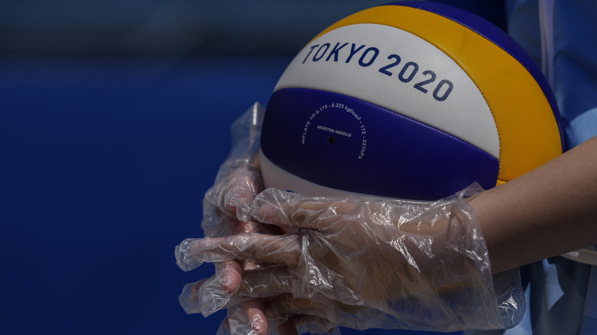 Védőkesztyűben tartja kezében a labdát egy önkéntes a világméretű koronavírus-járvány miatt elhalasztott 2020-as tokiói nyári olimpia férfi strandröplabda-tornája selejtezőjében játszott Brazilia-Argentina mérkőzésen a Siokaze Parkban 2021. július 24-én.