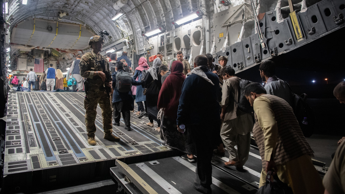 Az amerikai központi parancsnokság által közreadott képen afgánok beszállnak egy C-17 Globemaster III amerikai katonai teherszállító repülőgépbe a kabuli Hamid Karzai Nemzetközi Repülőtéren 2021. augusztus 22-én. Az Egyesült Államok és szövetségesei a légi kikötőn keresztül menekítik ki a külföldi állampolgárokat és a velük együttműködő afgánokat, miután az iszlamista tálibok elfoglalták Afganisztán csaknem egészét.