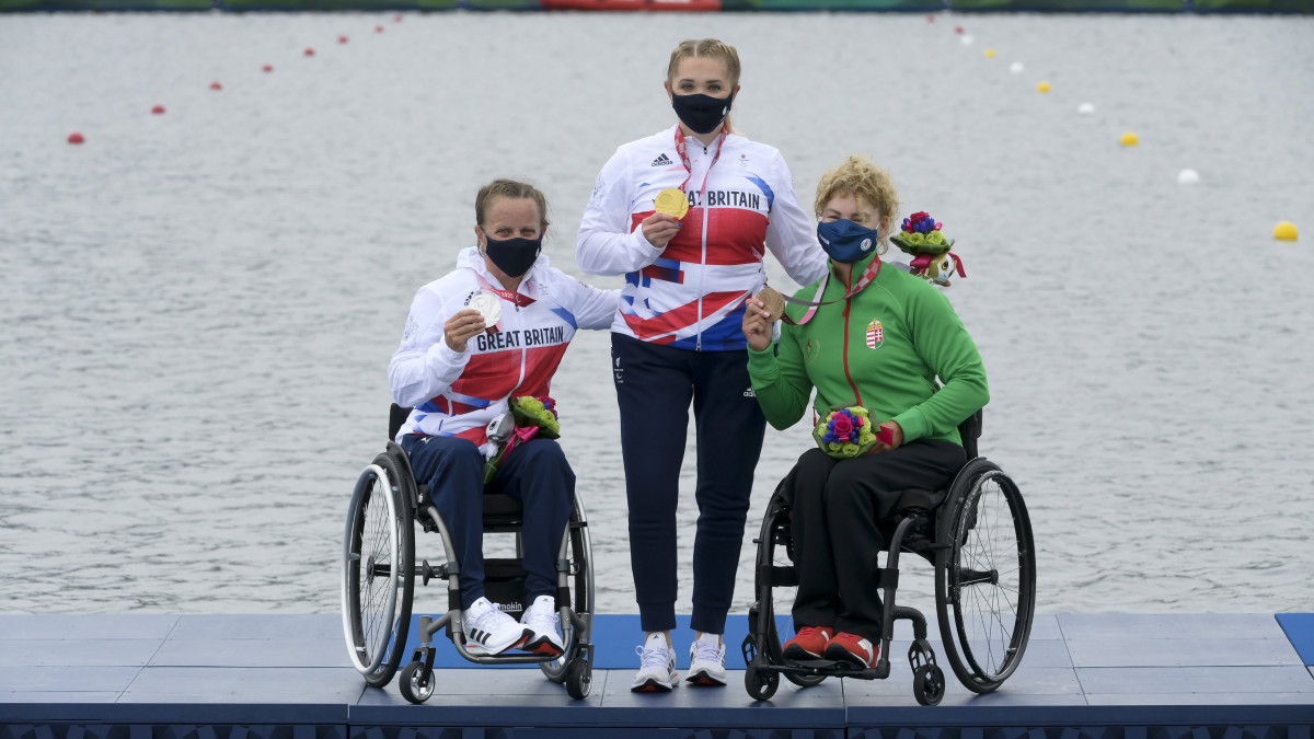 A győztes brit Charlotte Henshaw (k) és honfitársa, a második helyezett Emma Wiggs (b), valamint a bronzérmes Varga Katalin (j) a világméretű koronavírus-járvány miatt 2021-re halasztott 2020-as tokiói nyári paralimpia női kajak KL2 200 méteres versenyének az eredményhirdetésén a tokiói Sea Forest Evezős Pályán 2021. szeptember 4-én.