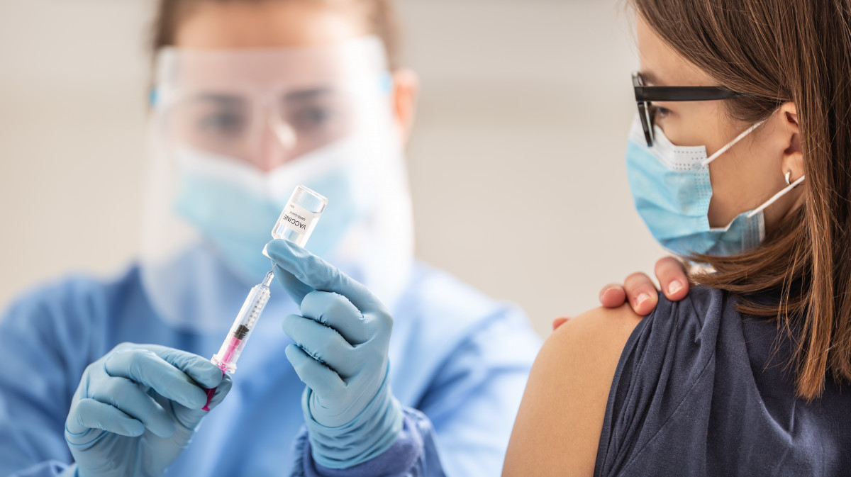 Young girl is waiting for her vaccination dose against coronavirus to be applied by a medical worker.