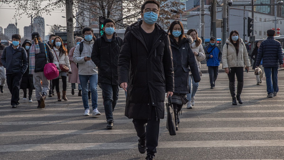 A koronavírus-járvány miatt védőmaszkot viselnek az emberek a reggeli csúcsforgalomban Pekingben 2021. február 24-én. Az egész világra kiterjedő koronavírus-járvány legelső, ismert gócpontja a közép-kínai Hupej tartomány székvárosa, Vuhan.