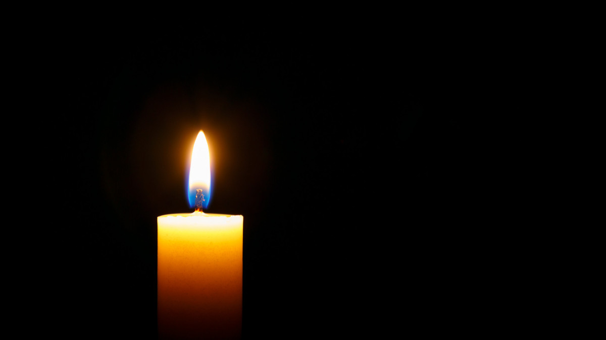 Burning candle on black background, space for text