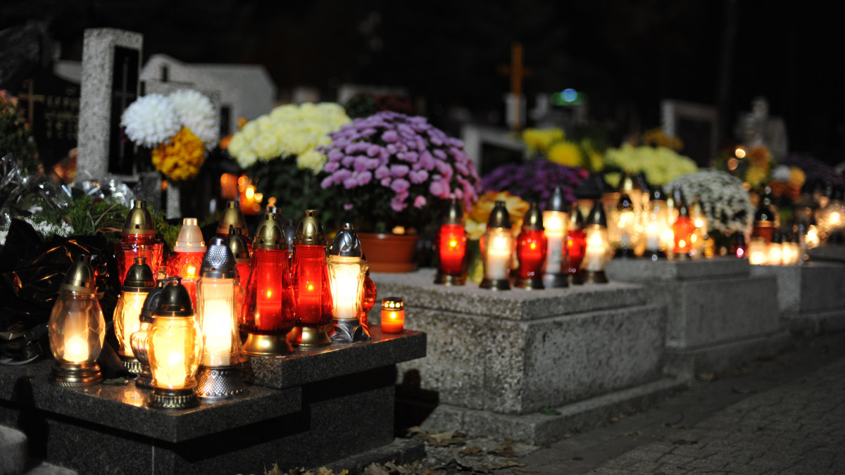 Candle lights on graves and tombstones in cemetery at night in Poland on All Saintsâ Day or All Soulsâ Day or Halloween or Zaduszki or Day of the Dead in Europe