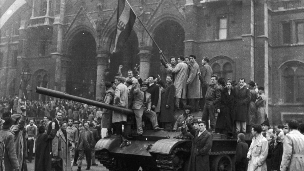 1956:  A group of men hold a flag on top of a tank in front of the Parliament building during the Hungarian Revolt, Budapest, Hungary.  (Photo by Hulton Archive/Getty Images)