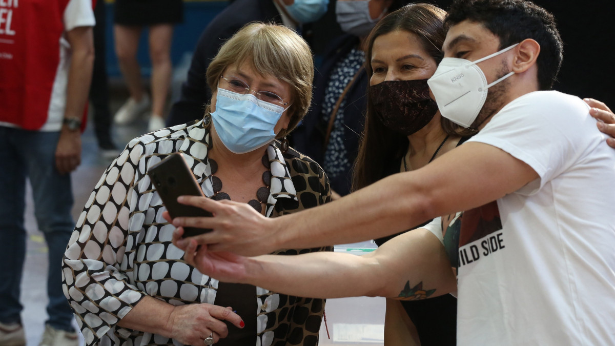 Michelle Bachelet, az ENSZ emberi jogi főbiztosa szelfit készít a választási bizottság két tagjával egy szavazóhelyiségben Chile fővárosában, Santiagóban 2021. december 19-én, az elnökválasztás második fordulójának napján.