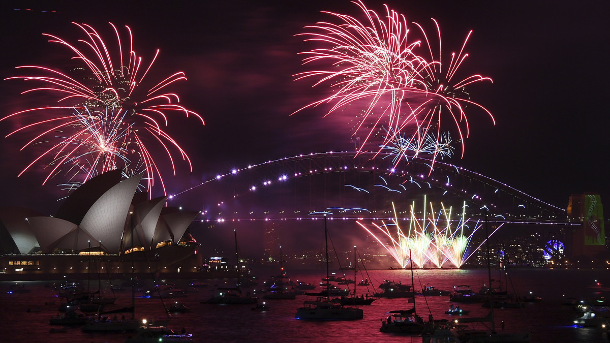 Tűzijátékkal köszöntik az új évet Sydney kikötőjében  2021. december 31-én, szilveszter éjszakáján. Középen a Harbour híd, balról az Operaház épülete.