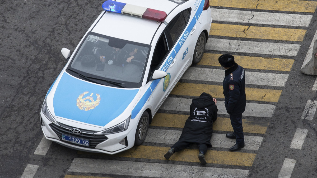 Földre fektetett autós papírjait ellenőrzik rendőrök Almatiban 2022. január 10-én, néhány nappal a tüntetők és a biztonsági erők közötti, több nappal korábbi heves összecsapások után. A leginkább Almatit érintették a zavargások, amelyek a cseppfolyós földgáz árának emelkedése miatt robbantak ki.