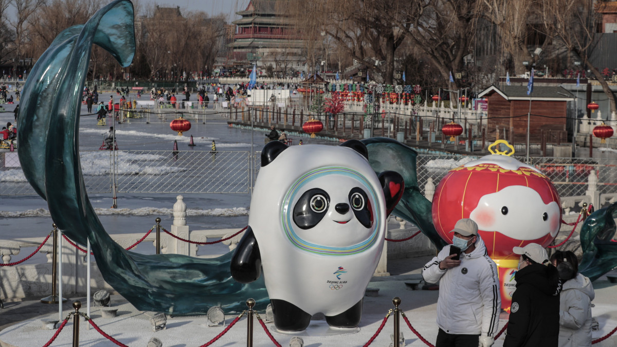 Védőmaszkos emberek Ping Tven Tven (b) és Suej Ron Ron, a 2022-es pekingi téli olimpia, illetve paralimpia kabalafigurája előtt Pekingben 2022. január 26-án. A kínai fővárosban február 4-20. között rendezik a 2022-es téli ötkarikás játékokat.