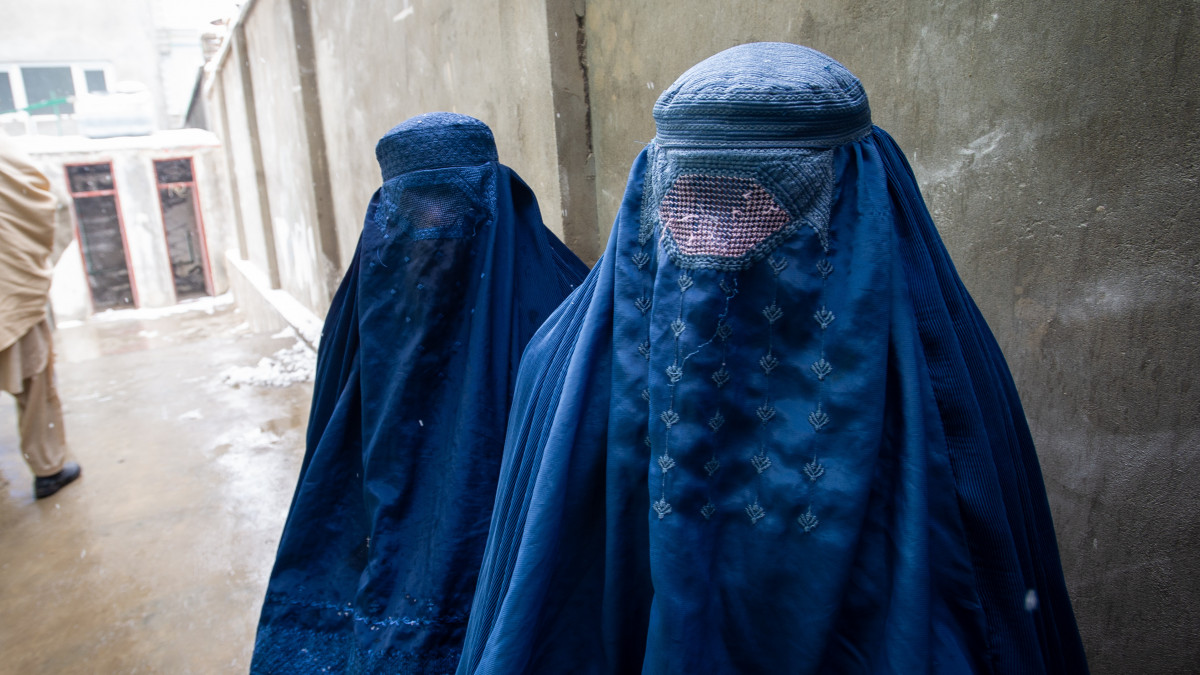 PUL-E ALAM, AFGHANISTAN -- JANUARY 17:  Two women wearing burqas pause for a portrait after having their ration cards checked, as the UN World Food Program (WFP) distributes a critical monthly food ration, with food largely supplied by the US Agency for International Development (USAID), to 400 families south of Kabul in Pul-e Alam, Afghanistan, on January 17, 2022. This food delivery to Logar province comes as the UN warns that 23 million Afghans, more than half the population, are on the verge of famine, following a severe drought and as winter deepens, while the US and World Bank have only partially released funds frozen when the Taliban took control of Afghanistan in August 2021. The UN has made an emergency appeal for $5.5 billion to feed the hungry and forestall further economic collapse.  (Photo by Scott Peterson/Getty Images)