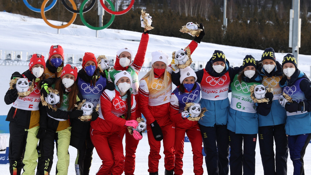 Az ezüstérmes német, az aranyérmes orosz, és a bronzérmes svéd csapat tagjai a pódiumon ünnepelnek a női sífutók 4x5 kilométeres váltójának eredményhirdetésén a 2022-es pekingi téli olimpián, a csangcsiakoui zónában lévő Nemzeti Sífutó Központban 2022. február 12-én.