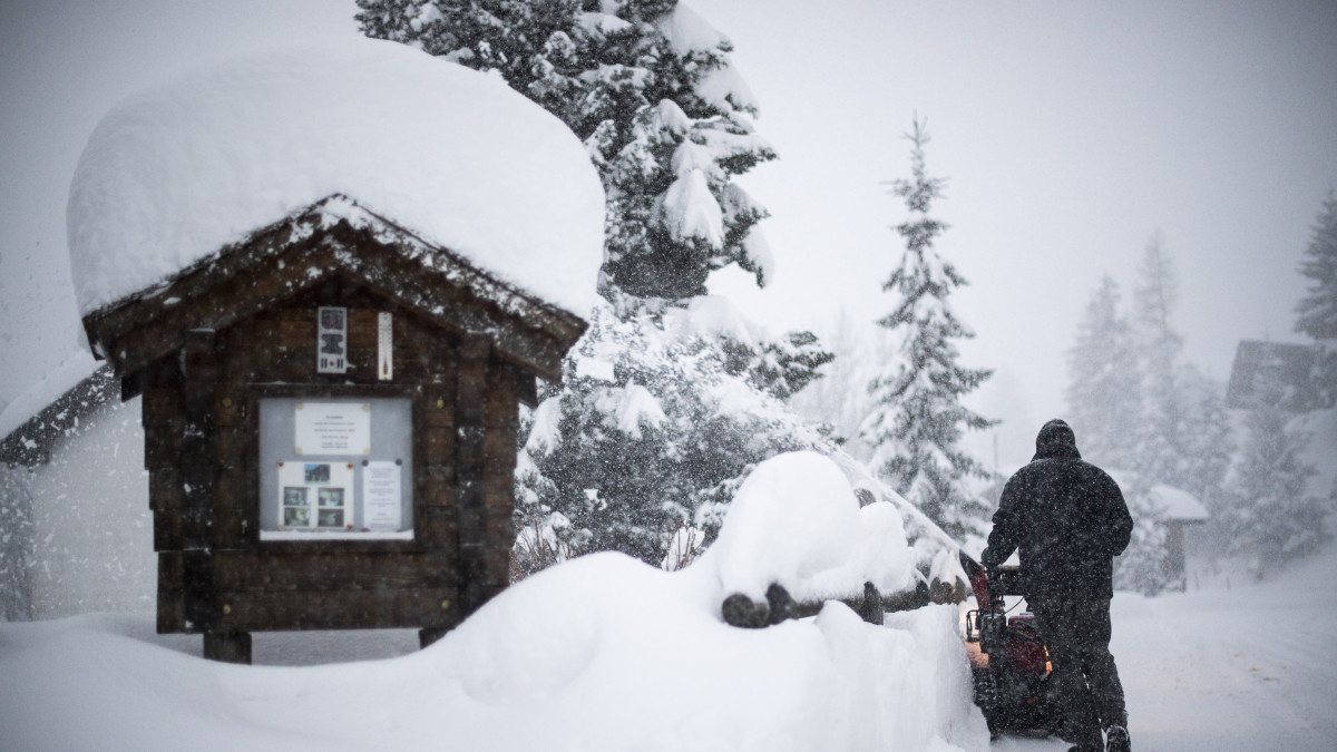 Hófúvógéppel takarítja a járdát egy férfi a svájci Sankt Gallen kantonban lévő Valens településen 2021. január 14-én. Az Alpok északi északi részén 80 centiméternyi friss hó hullhat a nap folyamán.