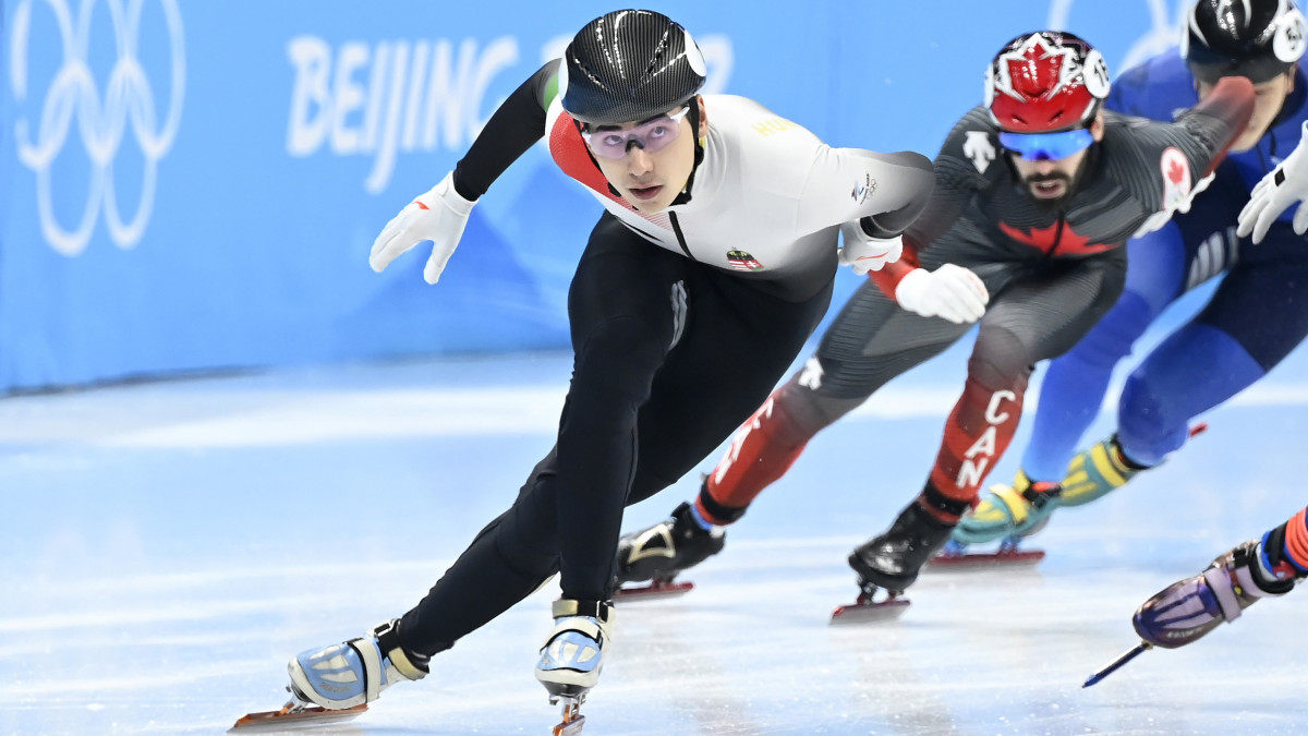 A későbbi győztes Liu Shaoang (b) a férfi rövidpályás gyorskorcsolyázók 500 méteres versenyének döntőjében a Fővárosi Fedett Stadionban a pekingi téli olimpián 2022. február 13-án. Mögötte a későbbi bronzérmes kanadai Steven Dubois (b2), valamint a kazah Abzal Azsgalijev (j).
