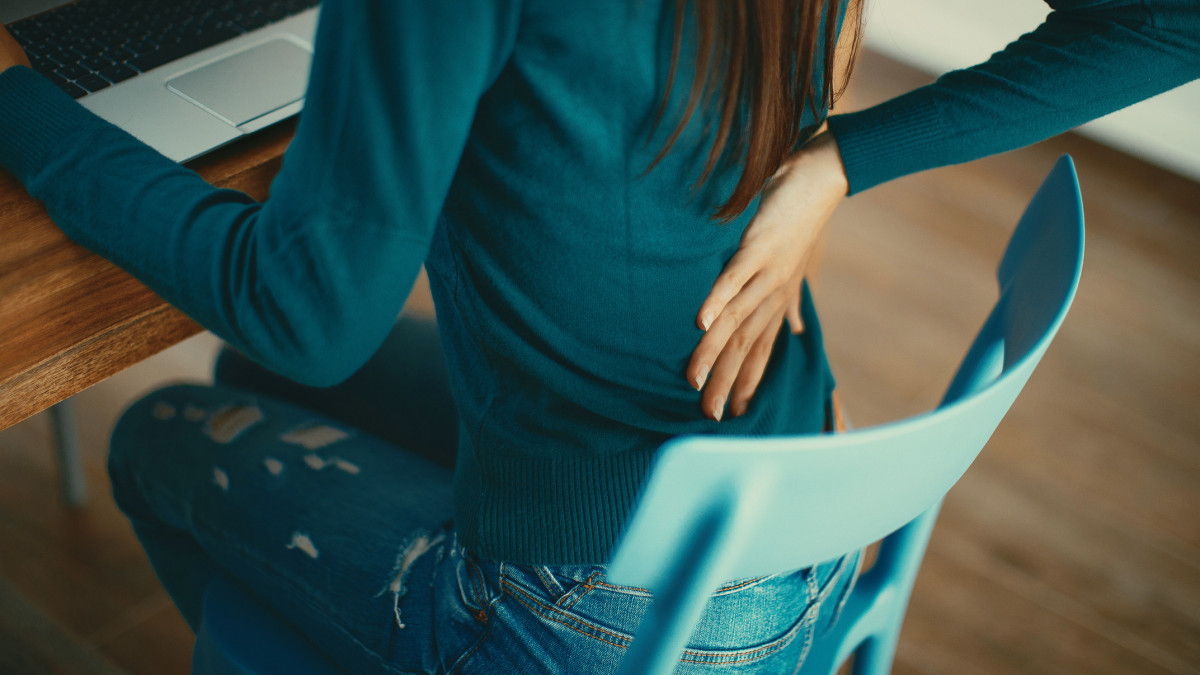 Close up of a brunette woman massaging her back