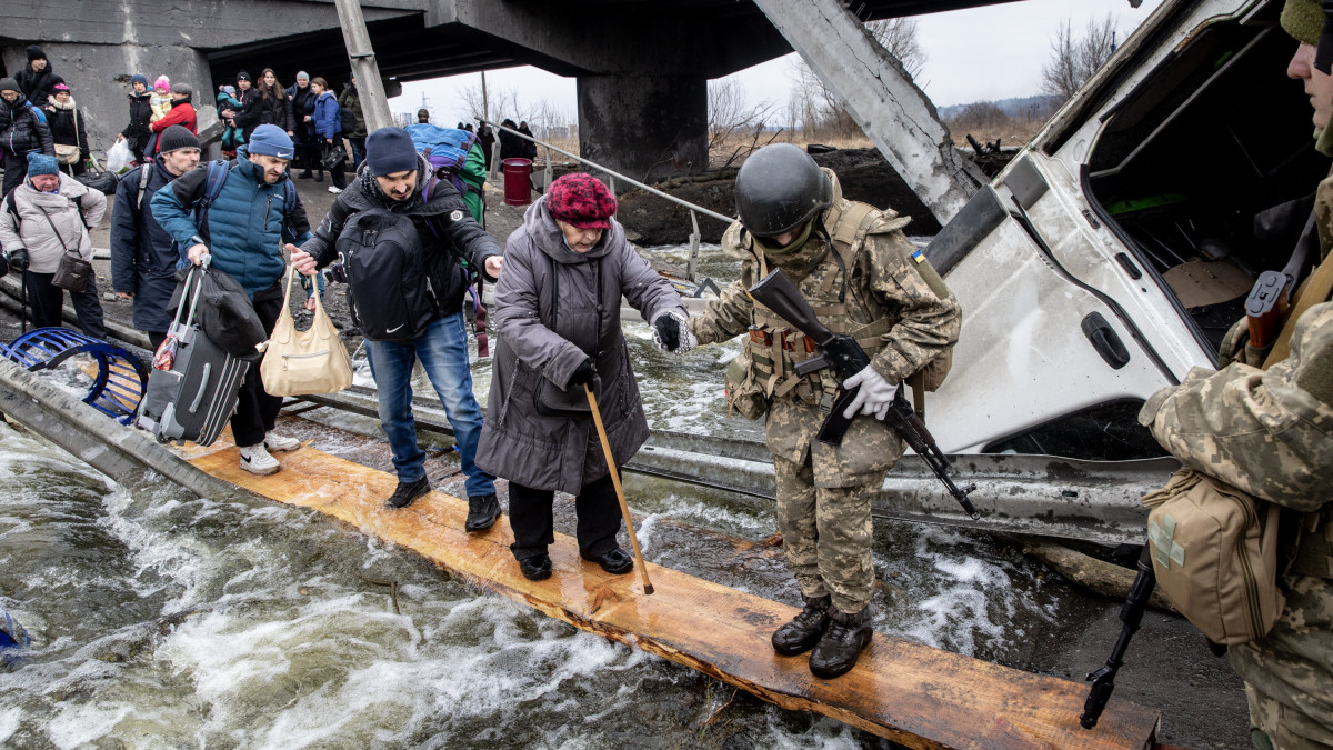 IRPIN, UKRAINE - MARCH 07: Residents of Irpin flee heavy fighting via a destroyed bridge as Russian forces entered the city on March 07, 2022 in Irpin, Ukraine. Yesterday, four civilians were killed by mortar fire along the road leading from Irpin to Kyiv, which has been a key evacuation route for people fleeing Russian forces advancing from the north. Today, Ukraine rejected as unacceptable a Russian proposal for a humanitarian corridor that leads from Kyiv to Belarus, a Russian ally that was a staging ground for the invasion. (Photo by Chris McGrath/Getty Images)