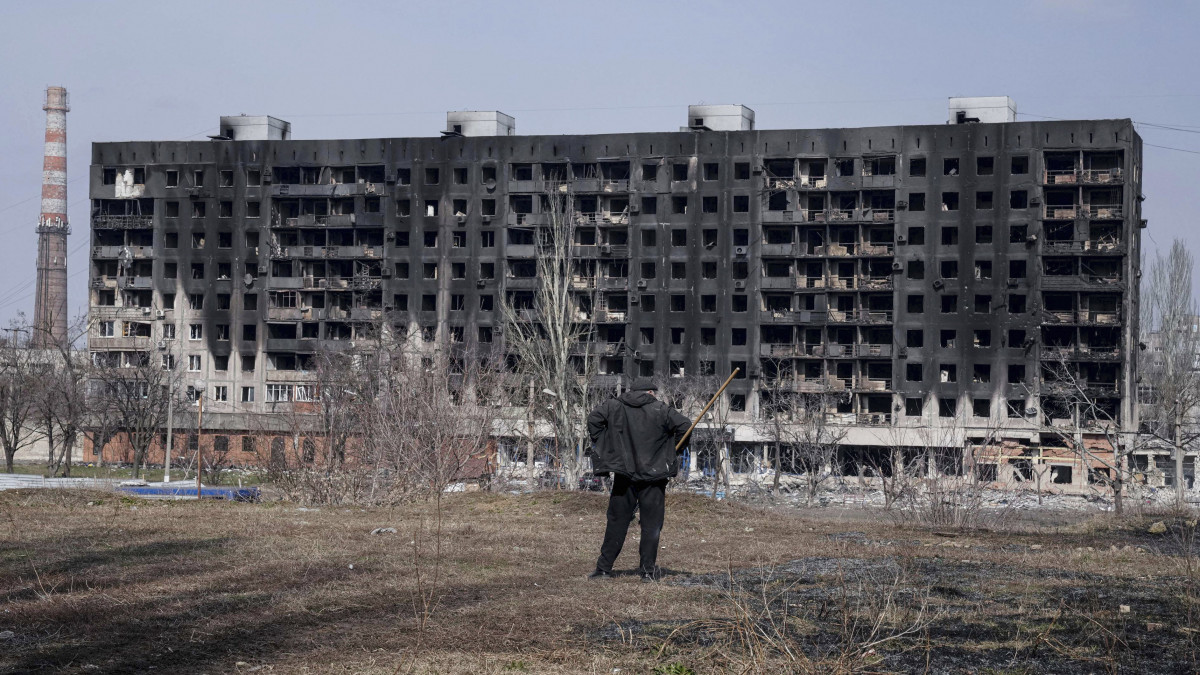 Tüzérségi támadásban megrongálódott lakóházat néz egy férfi Mariupolban 2022. március 13-án. Vlagyimir Putyin orosz elnök február 24-én rendelte el katonai művelet végrehajtását Ukrajnában.