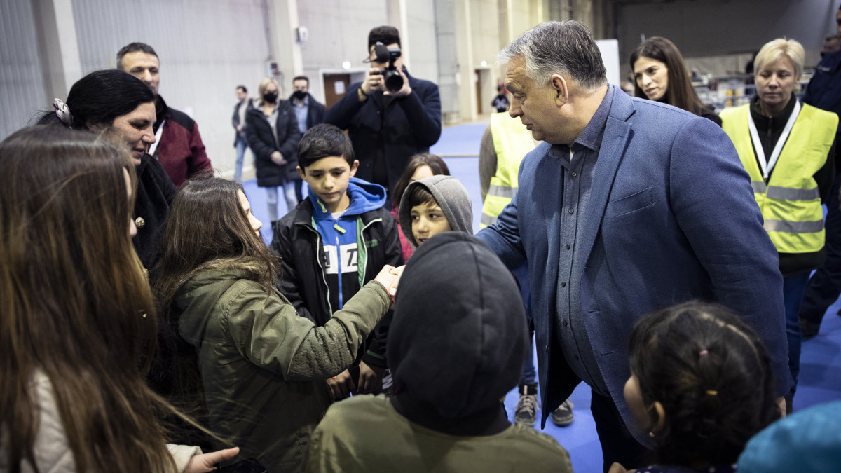 A Miniszterelnöki Sajtóiroda által közreadott képen Orbán Viktor miniszterelnök látogatást tesz a budapesti BOK csarnokban létesített humanitárius tranzitponton 2022. március 22-én. A tranzitpontot a kormány a karitatív szervezetekkel együttműködve nyitott meg az előző napon az ukrajnai menekültek számára. A kormányfő mögött Szentkirályi Alexandra kormányszóvivő (j2).