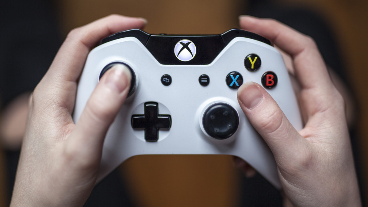Gothenburg, Sweden - January 17, 2015: A close up shot from above of a young womans hands holding a white Xbox One controller as she is playing a video game. Natural lighting, shot on wooden background with shallow depth of field.