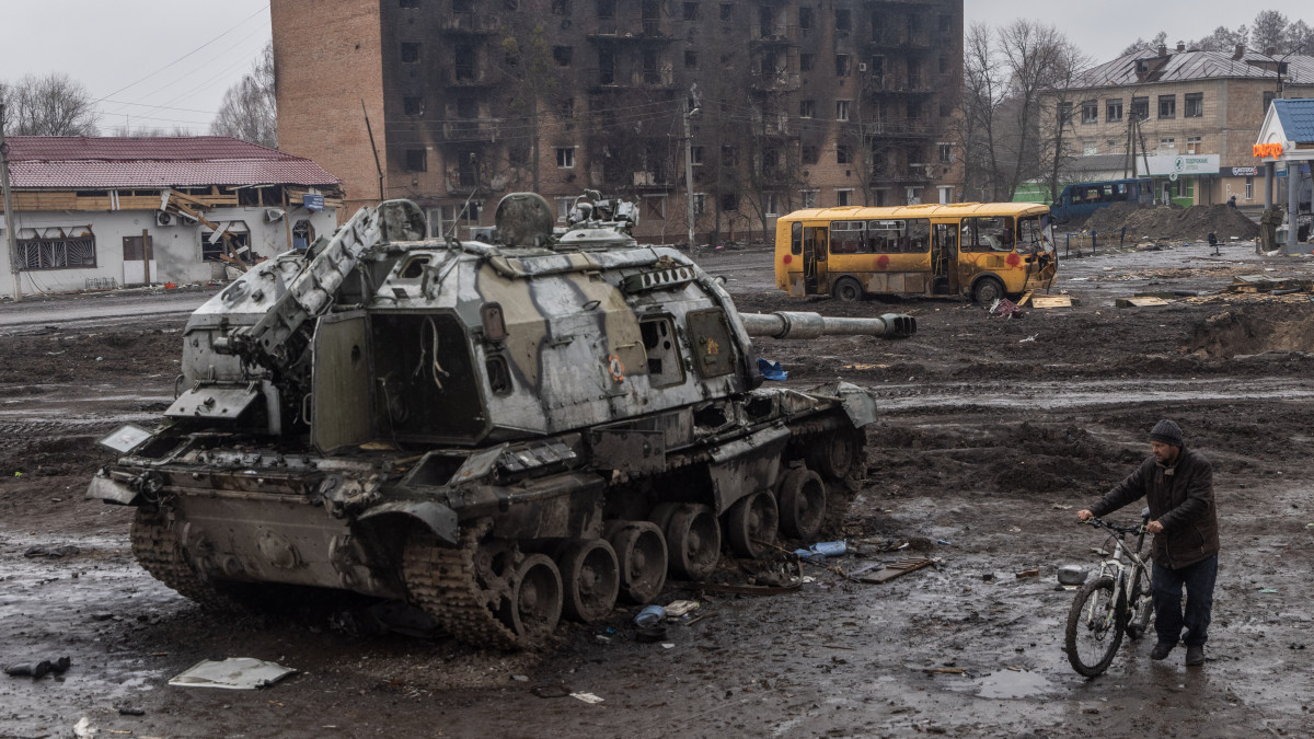 TROSTYANETS, UKRAINE - MARCH 30: A man pushes his bike through mud and debris past a destroyed Russian tank in front of the central train station that was used as a Russian base on March 30, 2022 in Trostyanets, Ukraine. Ukrainian forces announced this week that they had retaken Trostyanets, a northeastern town  that has seen fierce fighting and was occupied by Russians for weeks, from Russian control. Last week, after its advances have stalled on several fronts, Russia appeared to revise its military goals in Ukraine, claiming that it would focus its efforts on the battle in the eastern Donbas region. (Photo by Chris McGrath/Getty Images)