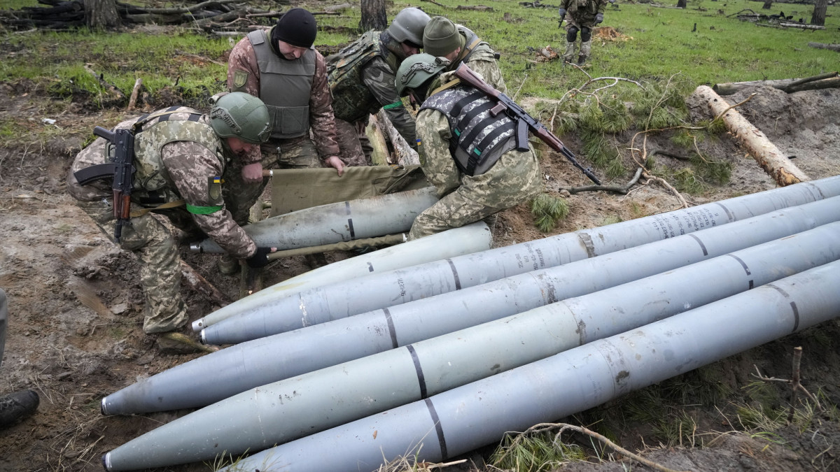 Ukrán katonák Uragan típusú rakétákat szednek össze az orosz támadások után Berezivkában 2022. április 21-én.