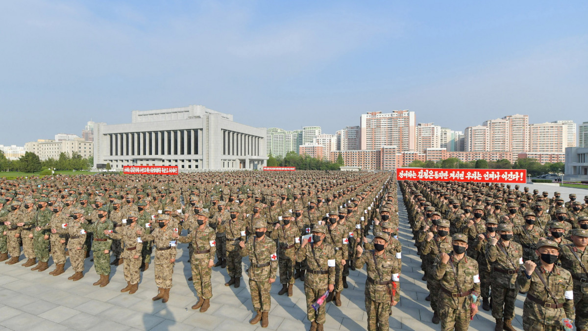 A KCNA észak-koreai állami hírügynökség által közreadott kép a Koreai Néphadsereg katonáiról  védelmi minisztérium épülete előtt Phenjanban 2022. május 16-án. A hadsereg feladata, hogy 24 órán belül eljuttassák a gyógyszereket a gyógyszertárakba a koronavírus-járvány terjedésének megfékezése érdekében. A KCNA jelentése szerint az előző 24 órában 392 920 ember kapta el a koronavírust az országban, összesen eddig 1 213 550-en fertőződtek meg, és 50-en meg is haltak, mióta az ország az előző héten elismerte, hogy ott is megjelent a koronavírus.