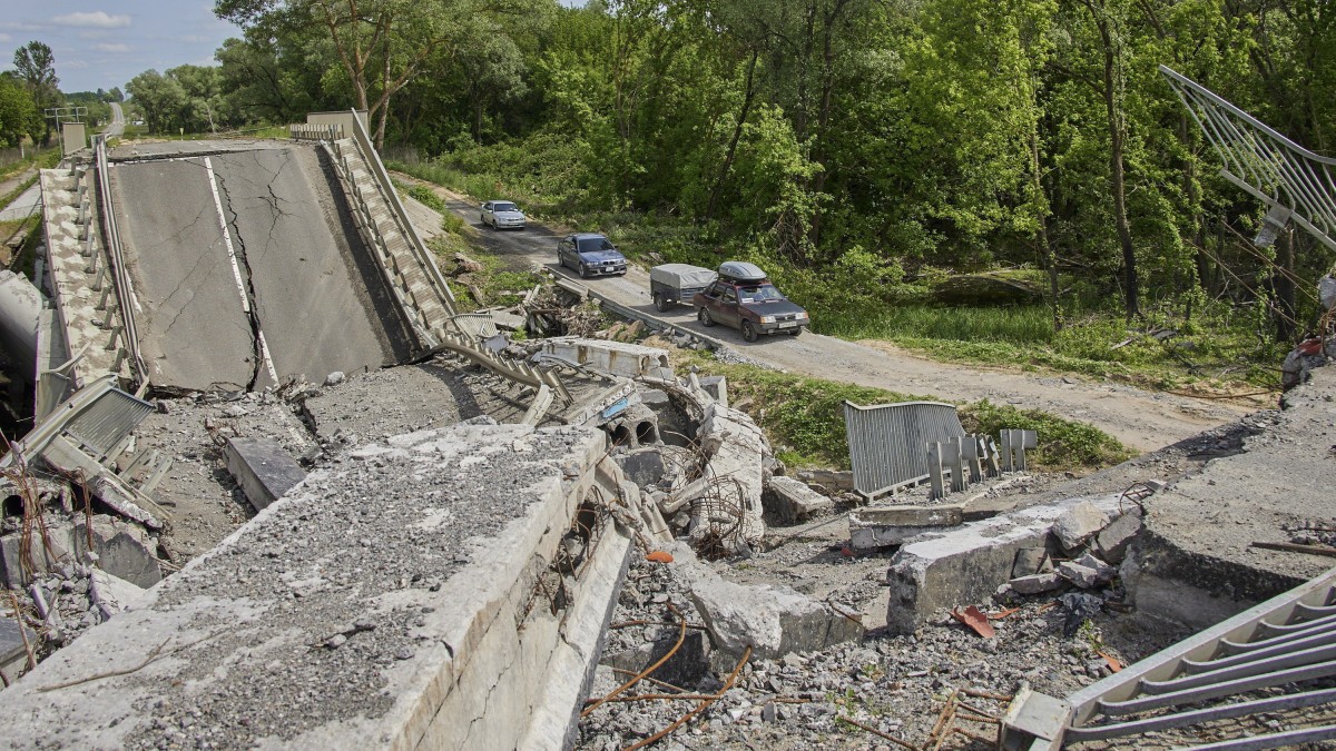 Lerombolt hídszakasz mellett hajtanak el civilek a kelet-ukrajnai Harkivban 2022. május 30-án, a várost ért újabb orosz támadás után. Az ágyúzásban három polgári lakos sérült meg, számos lakóházban és melléképületben keletkeztek károk.