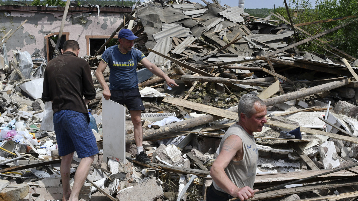 Az egyik éjszakai légicsapásban megsemmisült épület romjai között dolgoznak emberek a kelet-ukrajnai Szlovjanszkban 2022.május 31-én.