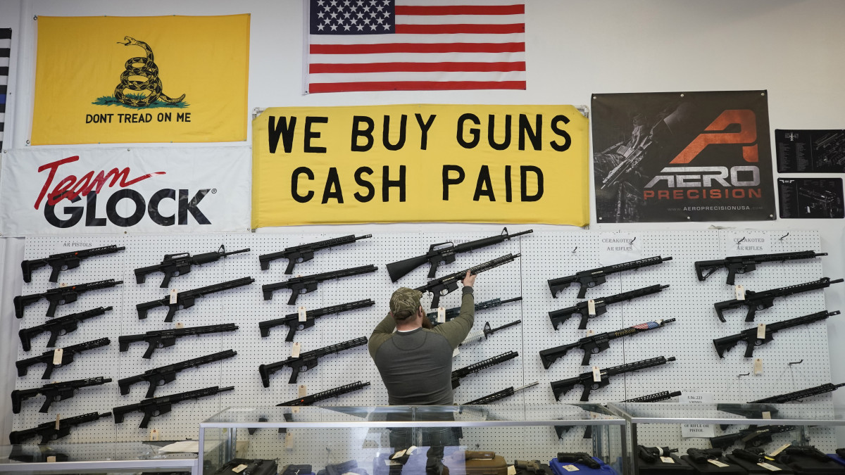 A salesperson takes an AR-15 rifle off the wall at a store in Orem, Utah, U.S., on Thursday, March 25, 2021. Two mass shootings in one week are giving Democrats new urgency to pass gun control legislation, but opposition from Republicans in the Senate remains the biggest obstacle to any breakthrough in the long-stalled debate. Photographer: George Frey/Bloomberg via Getty Images