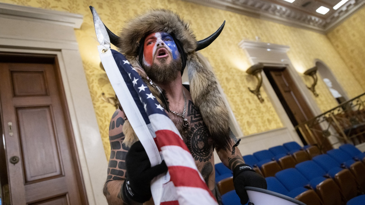 WASHINGTON, DC - JANUARY 06: Jacob Chansley, also known as the QAnon Shaman, screams Freedom inside the U.S. Senate chamber after the U.S. Capitol was breached by a mob during a joint session of Congress on January 6, 2021 in Washington, DC. Congress held a joint session to ratify President-elect Joe Bidens 306-232 Electoral College win over President Donald Trump. Pro-Trump protesters illegally entered the U.S. Capitol building following rallies in the nations capital. (Photo by Win McNamee/Getty Images)