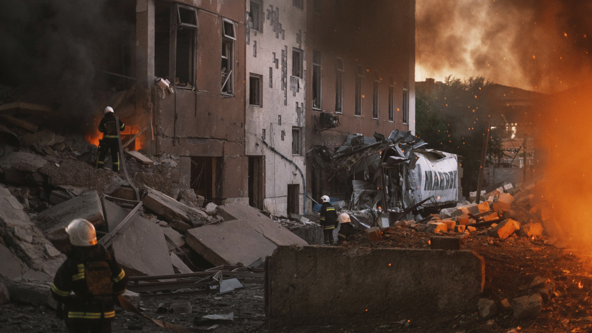 Lángoló épületnél tűzoltók a dél-ukrajnai Mikolajivban egy orosz tüzérségi támadás után, 2022. június 18-án.