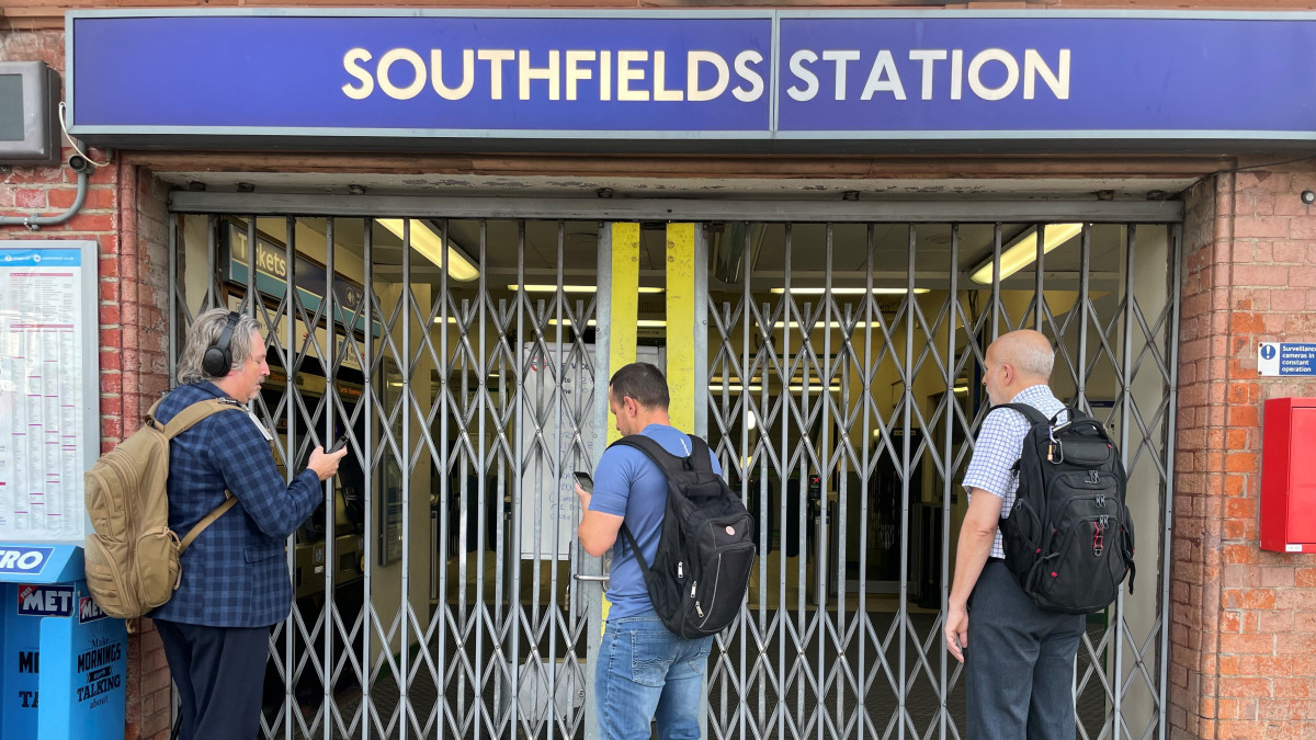 Passengers wait for the entrance gates to open at Southfields underground station in south London, the day after members of the Rail, Maritime and Transport union (RMT) from 14 train operators went on strike over jobs, pay and conditions. Picture date: Thursday July 28, 2022. (Photo by Joe Sene/PA Images via Getty Images)