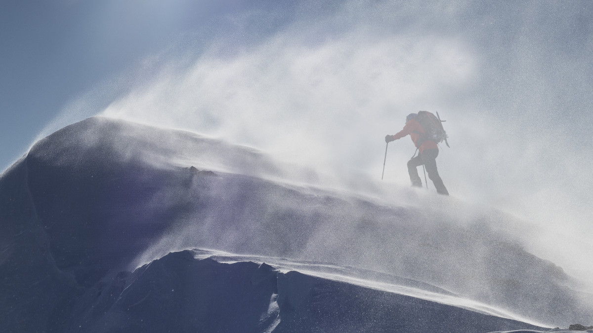Lone climber on a snowy ridge reaching a mountain summit in a snow storm in the Mont Blanc massif
