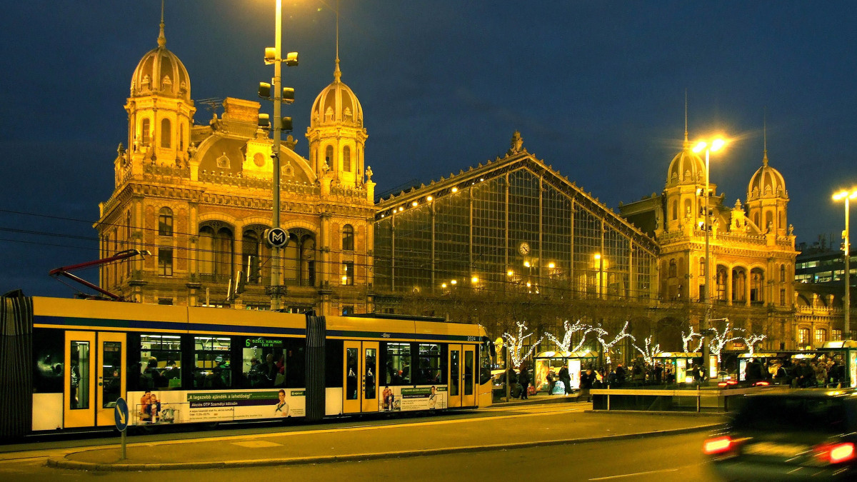 Budapest, 2016. december 9. Combino villamos halad át a Nyugati téren kora este. Mögötte a megvilágított Nyugati pályaudvar, karácsonyi fénydíszekkel. MTVA/Bizományosi: Jászai Csaba