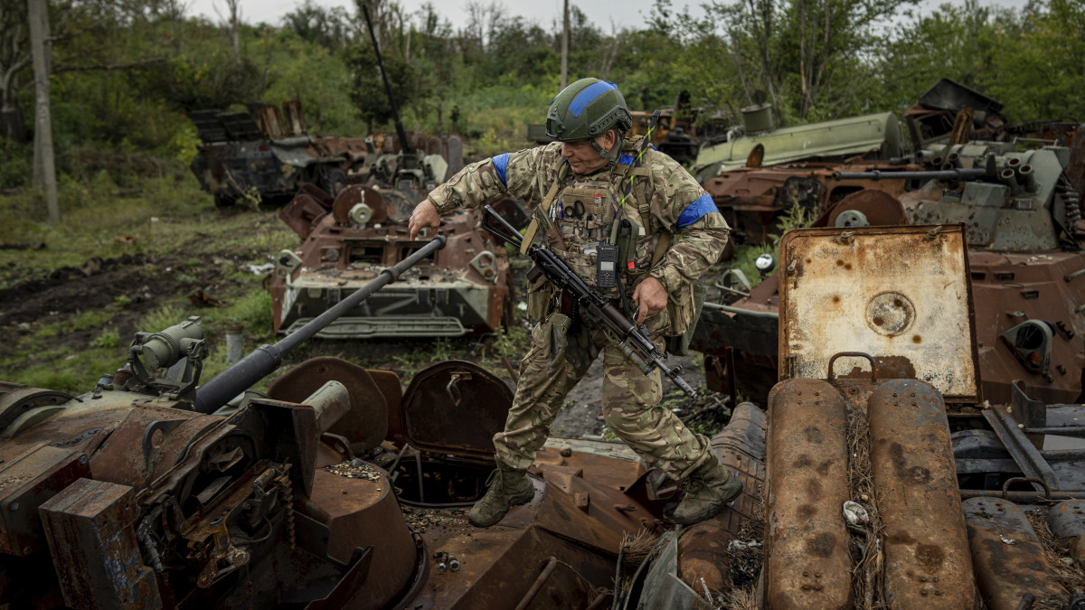 Kiégett orosz harcjárműveken lépdel egy ukrán katona a nemrégiben visszafoglalt Izjum város melletti erdőben, a kelet-ukrajnai Harkiv megyében 2022. szeptember 15-én.