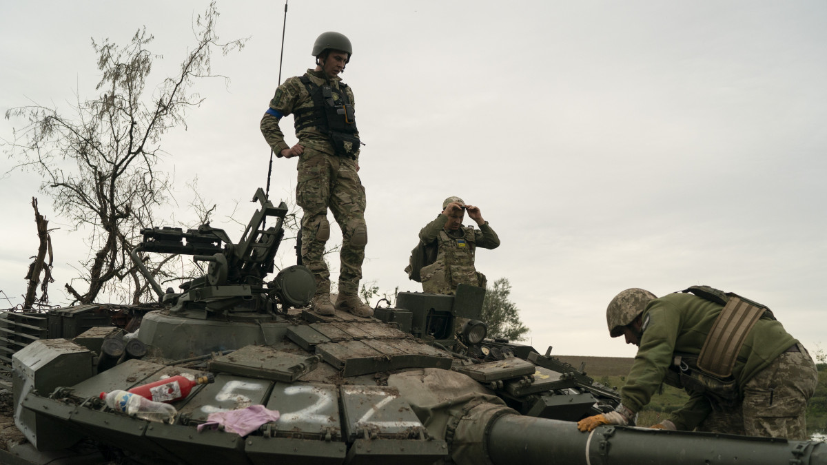 Ukrán katonák egy megsemmisített orosz harcjárművön a kelet-ukrajnai Harkivban 2022. szeptember 17-én.