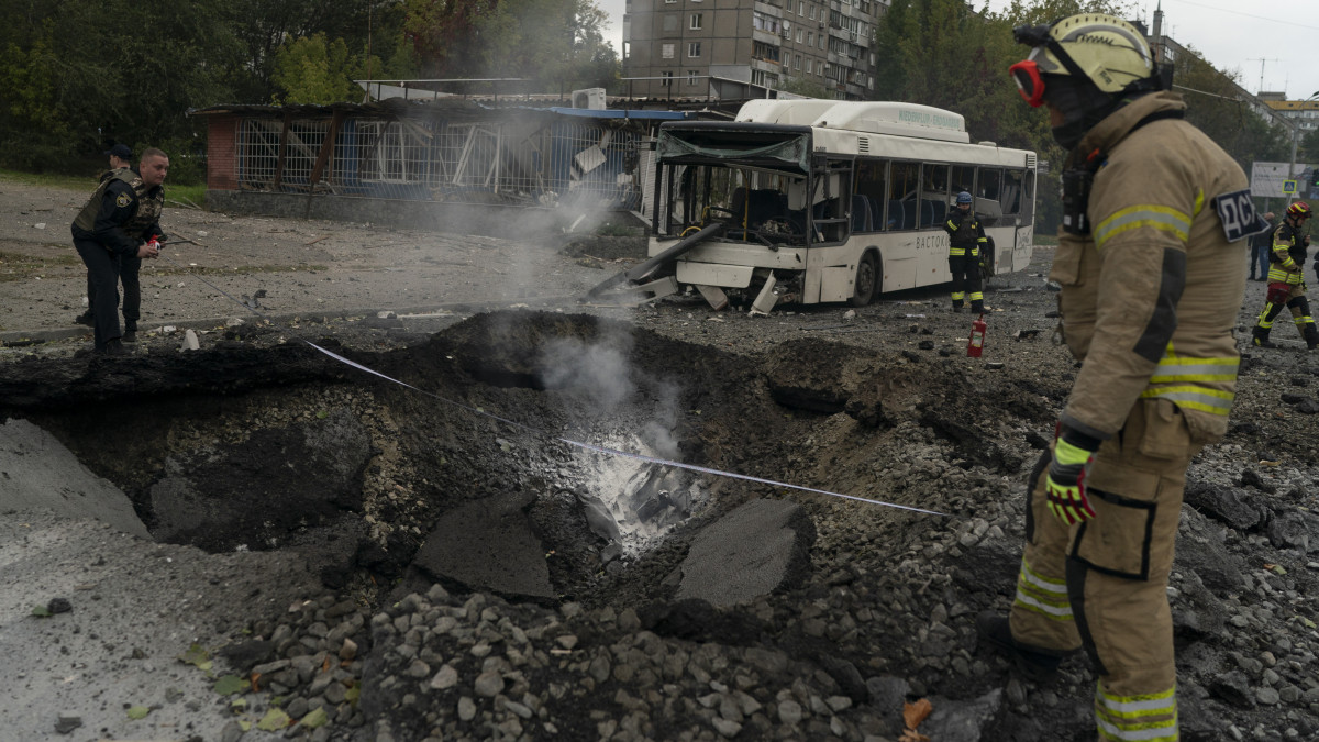 Bombatölcsér mellett tűzoltók és rendőrök Dnyipróban 2022. október 10-én, miután orosz rakétatámadás érte az ukrajnai várost.