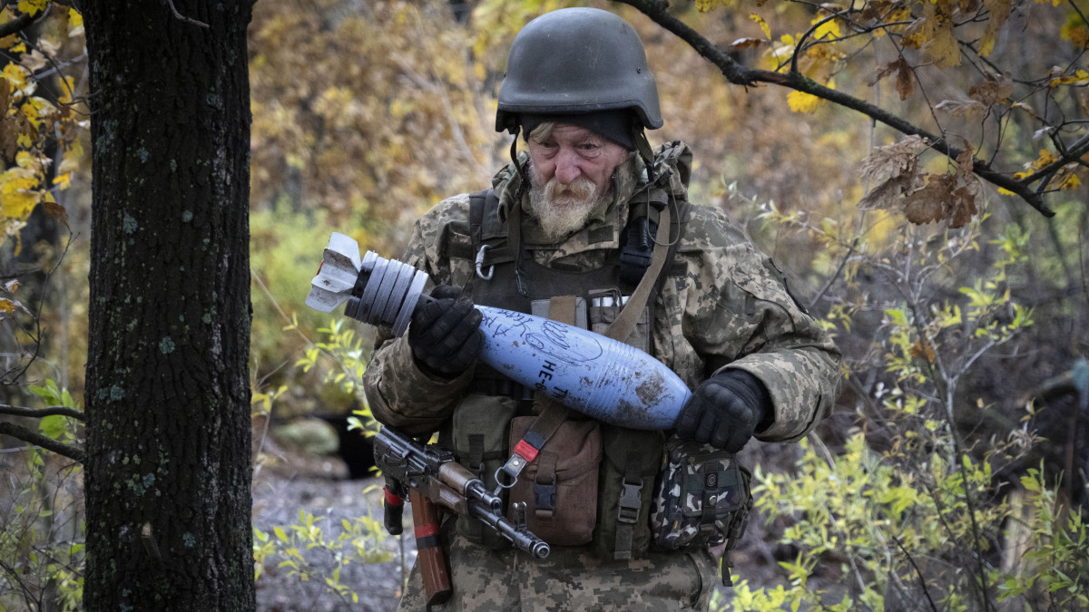 Ukrán tüzér aknagránátot visz, miközben egysége aknavetővel az orosz állásokat lövi a kelet-ukrajnai Donyecki területen fekvő Bahmut környékén 2022. október 27-én.