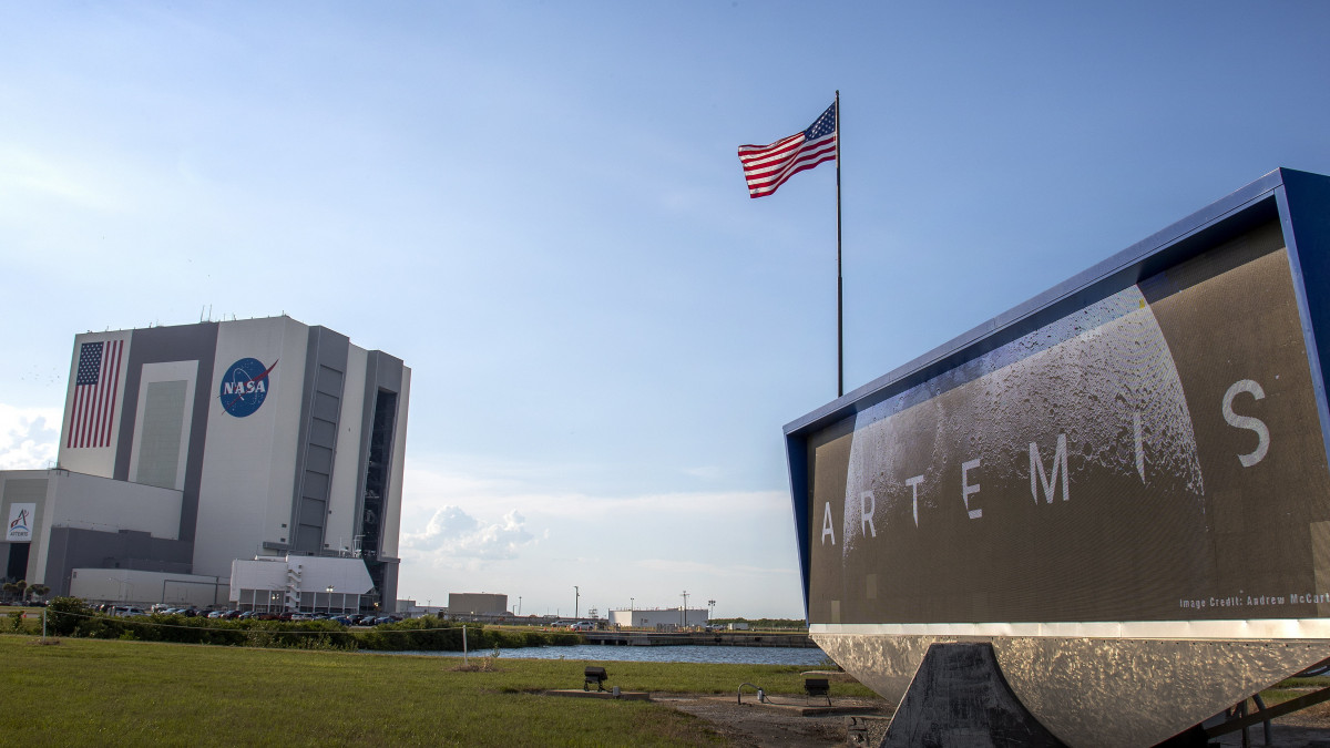 Az amerikai űrkutatási hivatal (NASA) szerelőcsarnoka (b), amelyből az Orion kapszulával felszerelt új SLS óriásrakétát a kilövőállásra szállítják a floridai Cape Canaveralnál működő Kennedy Űrközpontban 2022. augusztus 16-án. Az Artemis nevet viselő új űrprogram az első útján Hold körüli pályára állítja a legénységet egyelőre nem szállító Orion kapszulát, amely a tervek szerint mintegy 40 nappal később tér vissza a Földre. A NASA legkorábban augusztus 29-én indítja útnak az SLS óriásrakétát tesztelő Artemis 1-et.