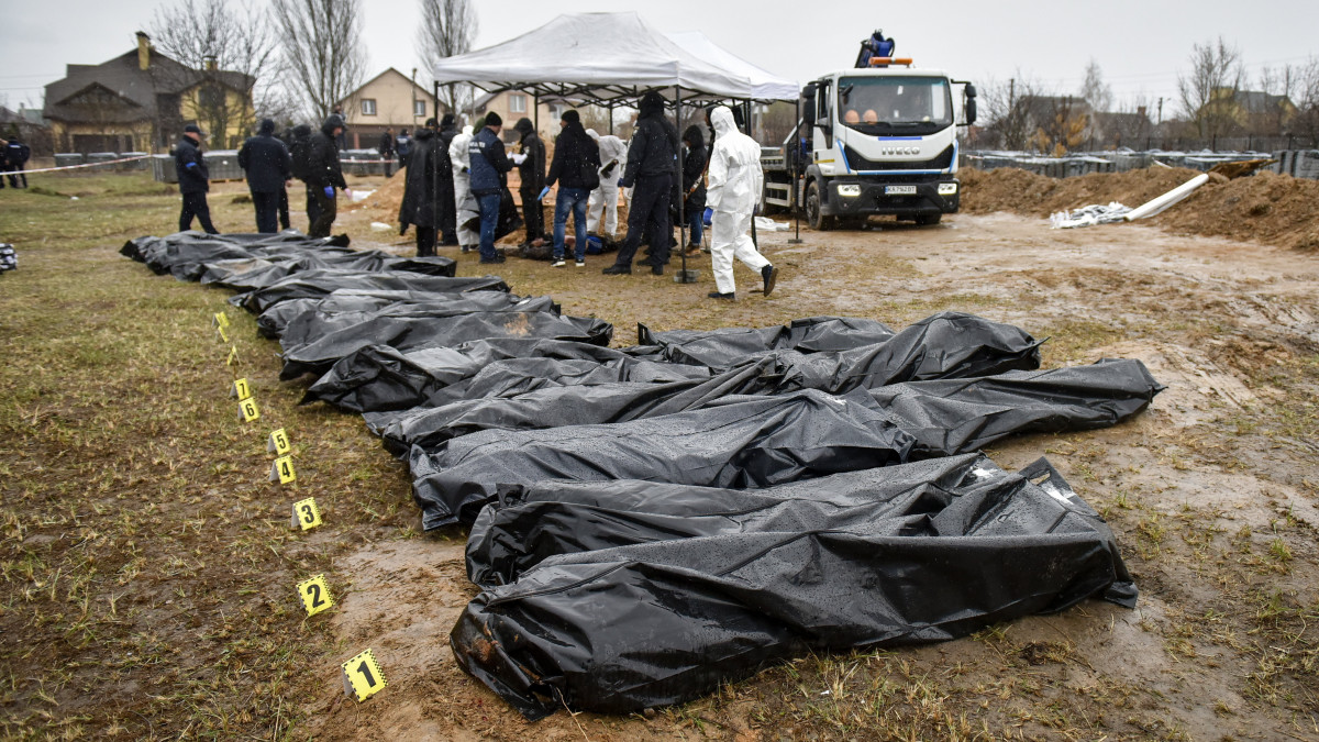 Hatósági személyek tömegsírból kihantolt emberek nejlonzsákba helyezett holttestei mellett a Kijev melletti Bucsában 2022. április 8-án. Az ukrán hatóságok napokkal ezelőtt Kijev környékén készült fényképeket és videófelvételeket tettek közzé, amelyeken számos, utcán fekvő, civil ruhás ember holtteste látható. Az orosz kormány ukrán szélsőségesek provokációjának minősítette a történteket.